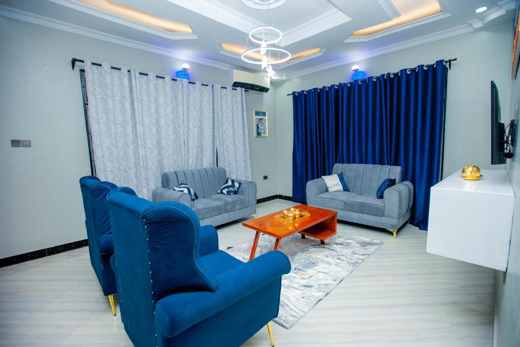 a living room with blue chairs and a table at Niwa Apartments in Dar es Salaam