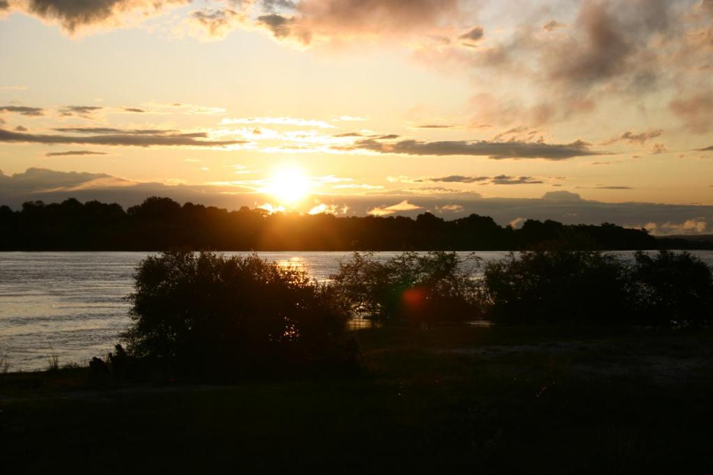 a sunset over a body of water with the sun setting at Zambezi Family Lodge in Victoria Falls