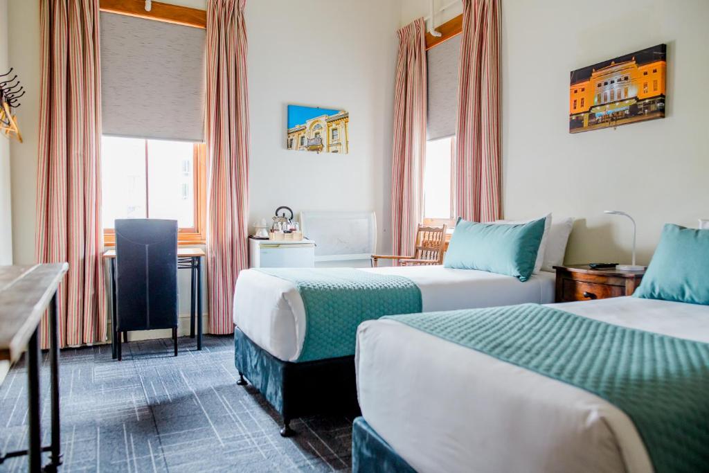Habitación de hotel con 2 camas y mesa en The Cambridge Hotel en Wellington