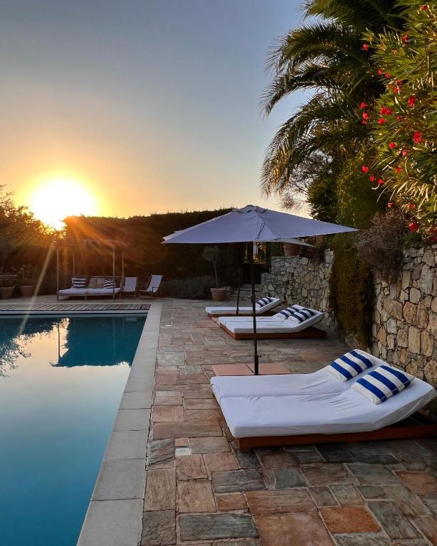 - une piscine avec un parasol et des chaises longues à côté de la piscine dans l'établissement Le Mouron Rouge, à La Garde-Freinet