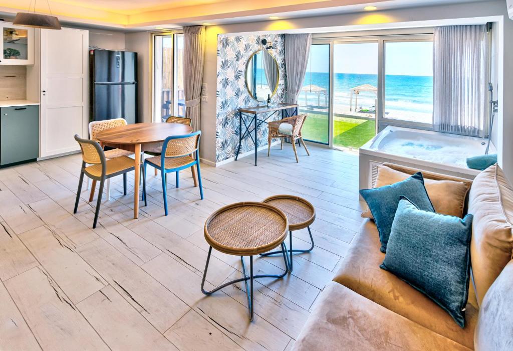 בית חוף מושלם עם גקוזי ומרפסת - Beachside Bliss W jacuzzi في حيفا: غرفة معيشة مع أريكة وطاولة