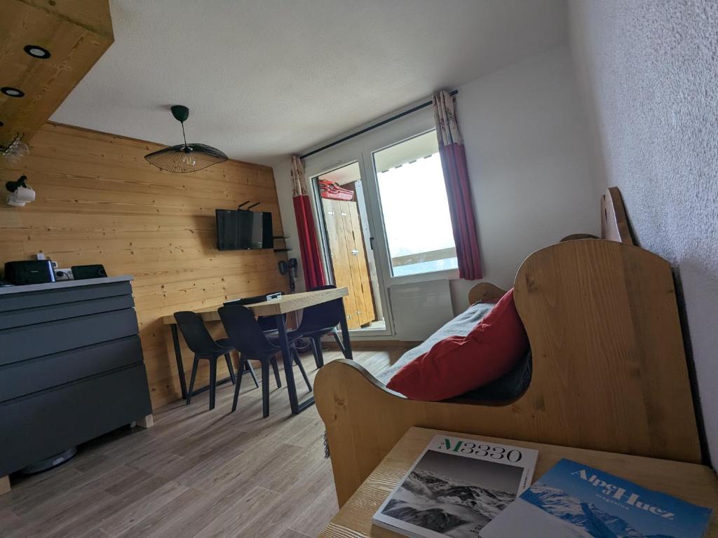 Una habitación con una cama y una mesa y una cocina. en Ecrin Alpe d'huez, en LʼHuez