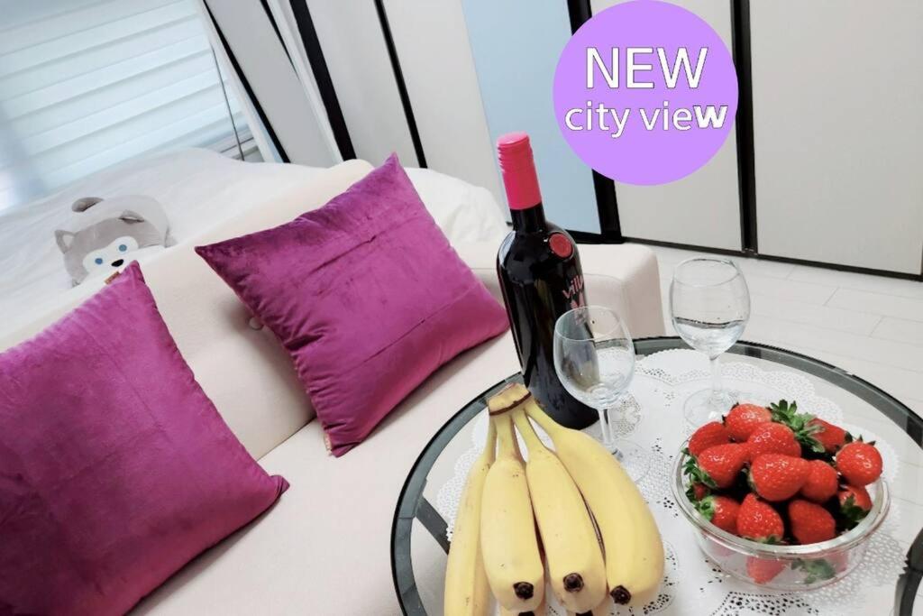 einen Tisch mit einer Schale Obst und einer Flasche Wein in der Unterkunft For you House in Daegu