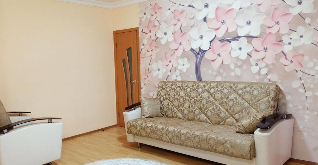 a couch in a living room with a flower wall at 2-х комнатная квартира in Balqash