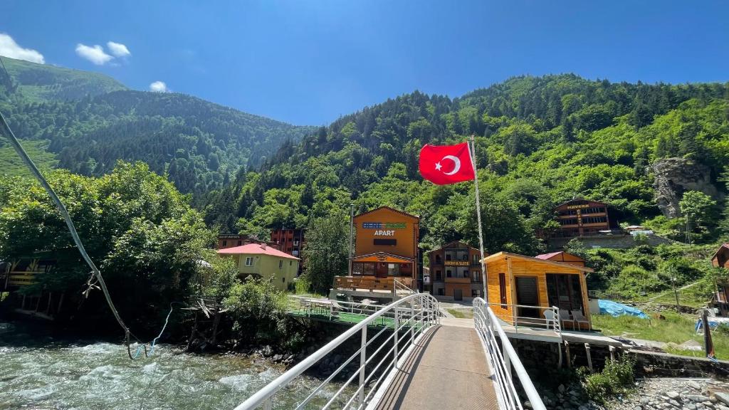 een vlag op een brug over een rivier met een berg bij Derepark Apart in Uzungol