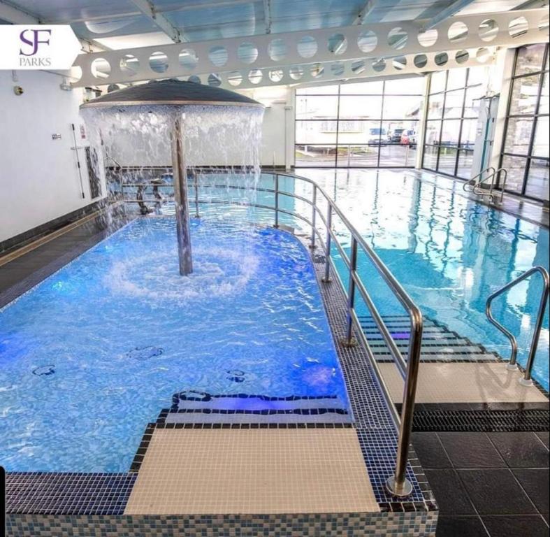 a large swimming pool with a fountain in a building at The mistral golden gate towyn in Kinmel Bay