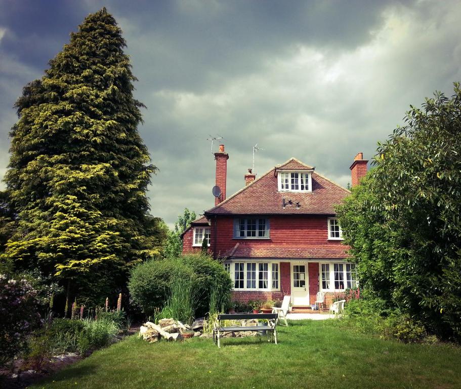 a house with two trees and a bench in the yard at Rosemead Guest House in Claygate