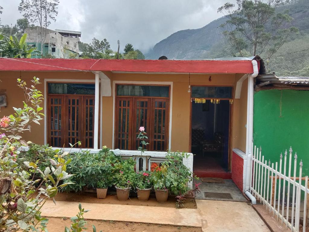 a small house with a red roof and some plants at Dilani Adamspeak RiverStay in Adams Peak
