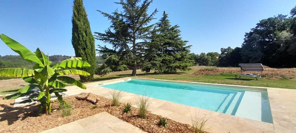 una piscina en un patio con un banco y árboles en Gite LOT'ivier Piscine et Lot 2 à 4 pers, en Montayral