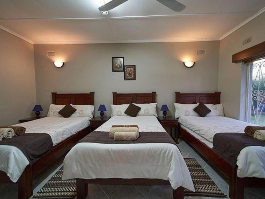 a bedroom with two beds with white sheets at Room in Villa - Zambezi Family Lodge - Rhino Room in Victoria Falls