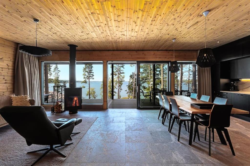 a dining room with a table and chairs and a fireplace at Saunamäki Resort K - Luxury Designer Seafront Villa in Salo