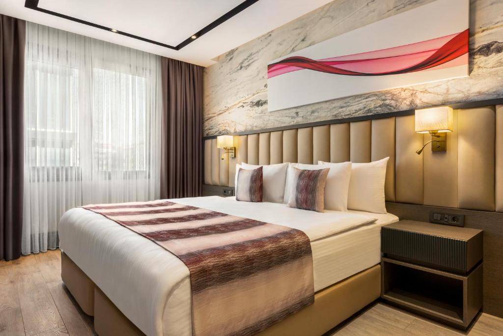 a hotel room with a bed and a painting on the wall at Ramada by Wyndham Istanbul Umraniye in Istanbul