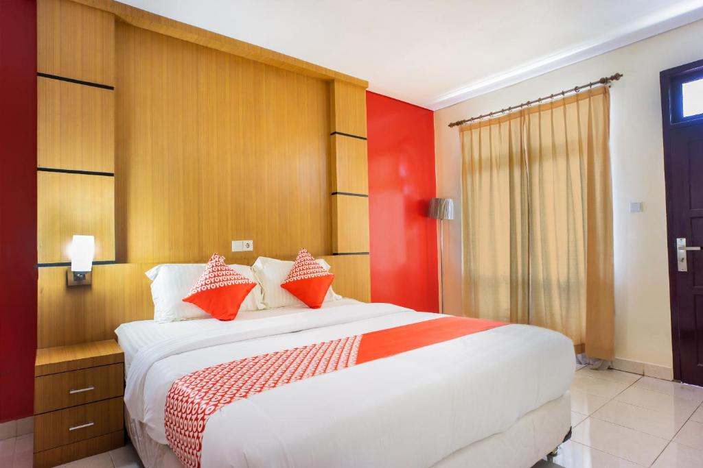 um quarto com uma grande cama branca com detalhes em vermelho em OYO 1636 Wisma Kuta Karang em Lhokseumawe