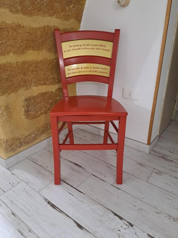 una silla roja en la parte superior de un suelo de madera en La Sedia Rossa Historical Centre, en Agrigento