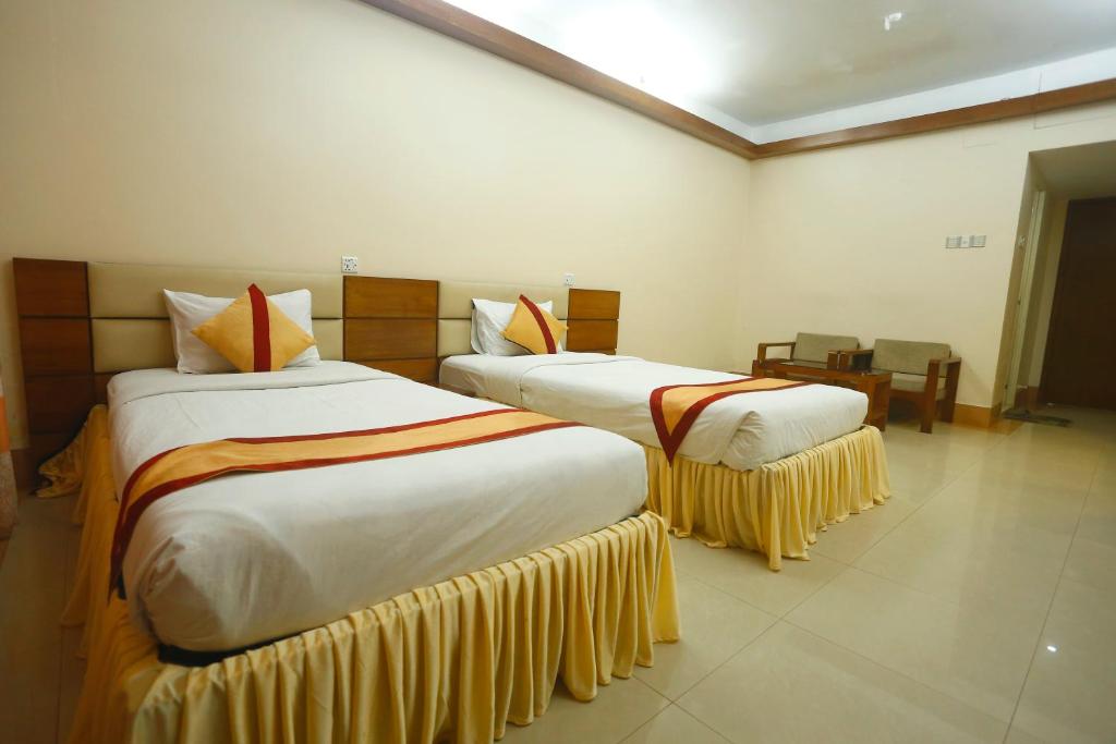 two beds in a hotel room withskirts at Hotel Garden Inn in Sylhet