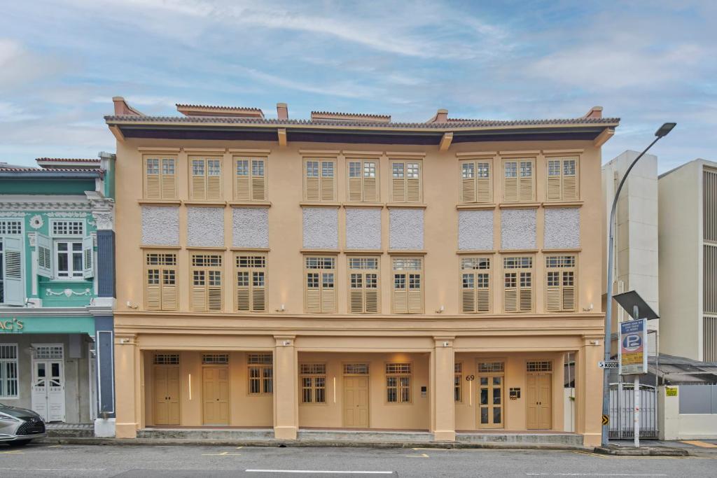 a large yellow building with windows on a street at KINN Studios in Singapore