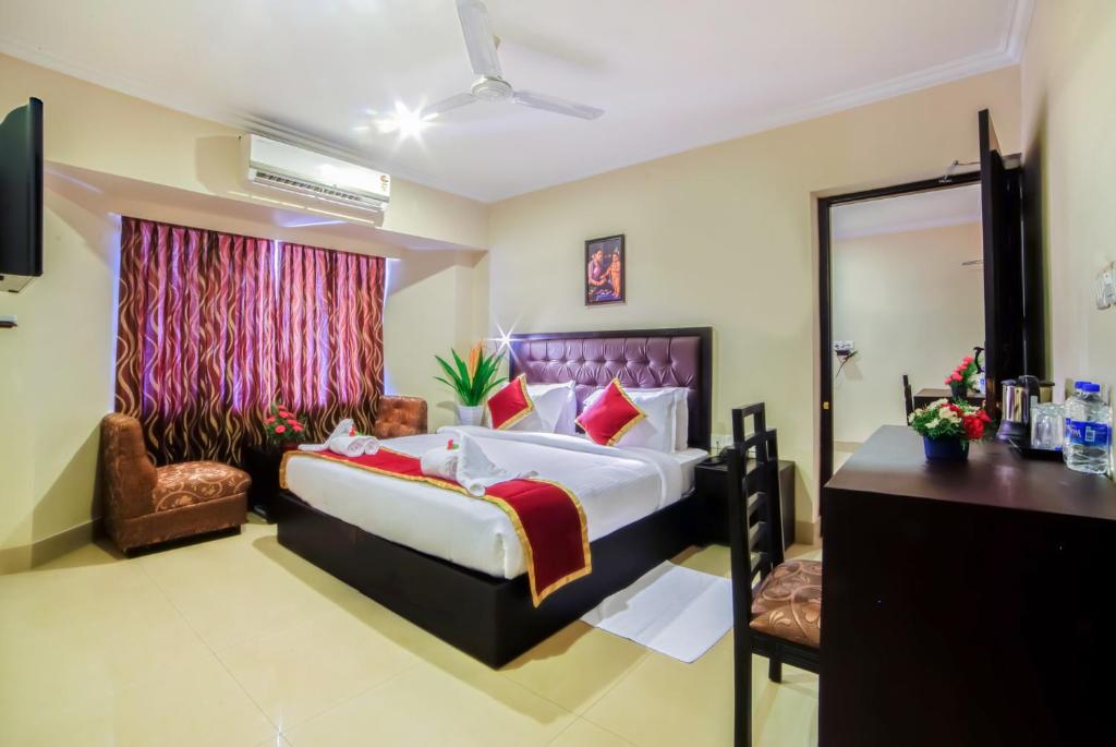una habitación de hotel con una cama grande y una silla en Chirag Inn en Thiruvananthapuram