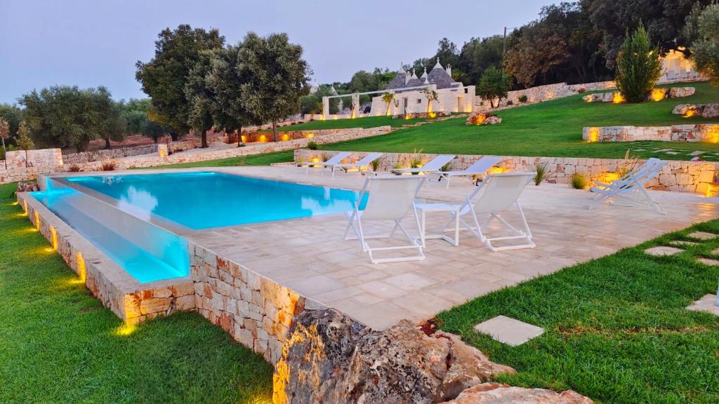 a pool with chairs and a table in a yard at Borgo Petra in Cisternino