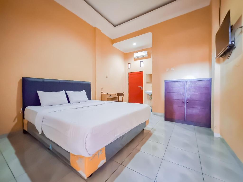 a bedroom with a large bed and a purple door at RedDoorz near Kantor Gubernur Kalimantan Tengah in Palangkaraya