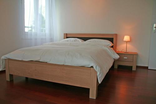 a bed in a bedroom with a nightstand and a lamp at Nest - Feldhof 5 in Zug