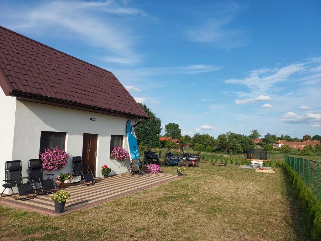 Casa blanca pequeña con terraza de madera en Domki u Anety, en Górkło