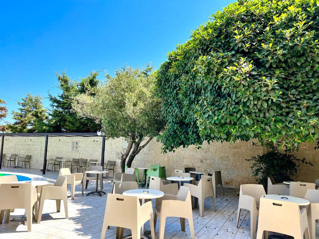a patio with tables and chairs and a tree at Karteros Hotel in Karteros