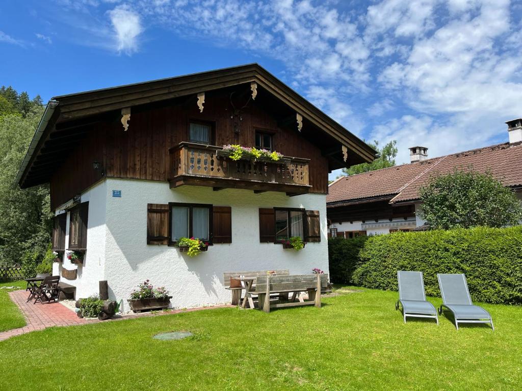 una casa con dos sillas y un banco en el patio en Ferienhaus Anni, en Kreuth