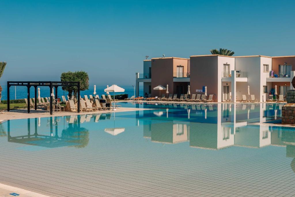 ein Pool in einem Resort mit Stühlen und Gebäuden in der Unterkunft Atlantica Akteon in Paphos City