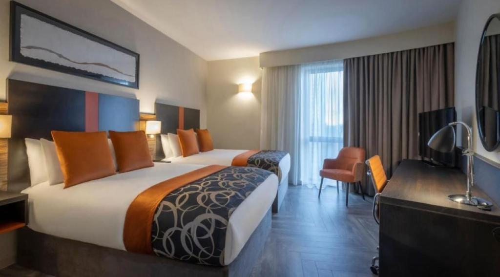 una camera d'albergo con due letti e una televisione di Clayton Hotel Cardiff a Cardiff