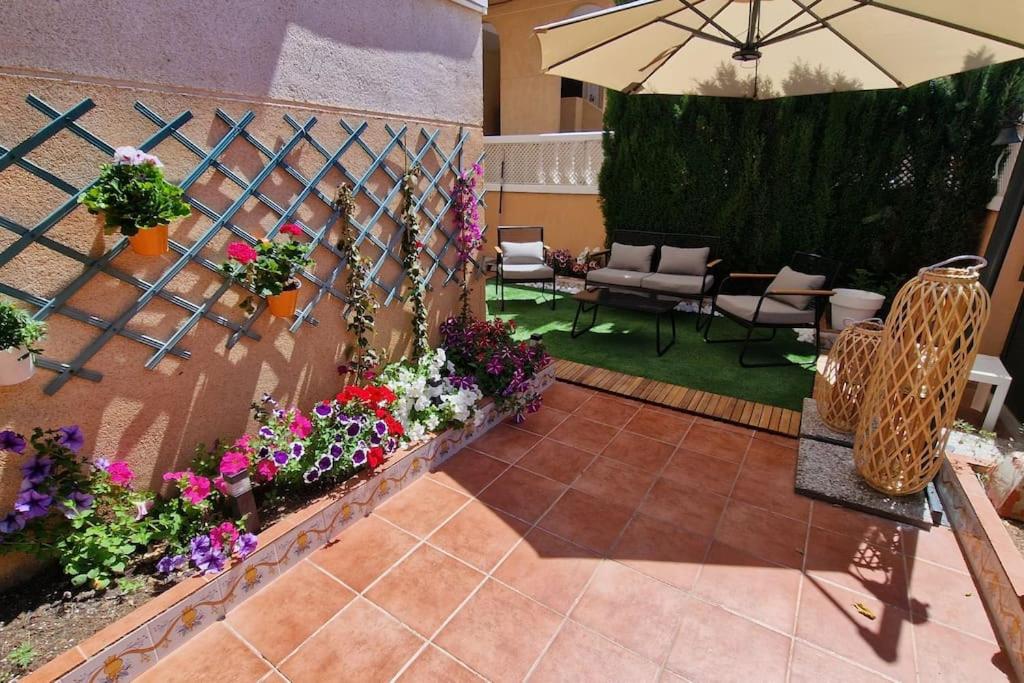 patio z kwiatami i parasolem w obiekcie 'Rincón exquisito' junto al mar w mieście Moncófar