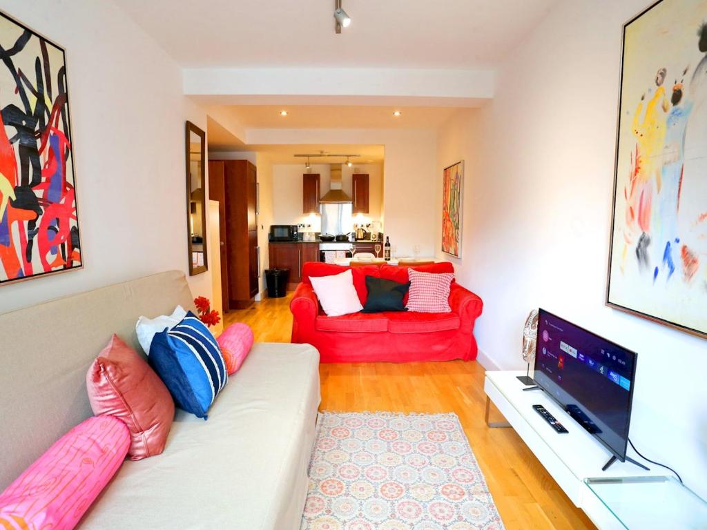 a living room with a white couch and red chairs at Pass the Keys Bohemian Ancoats suite with balcony in Manchester