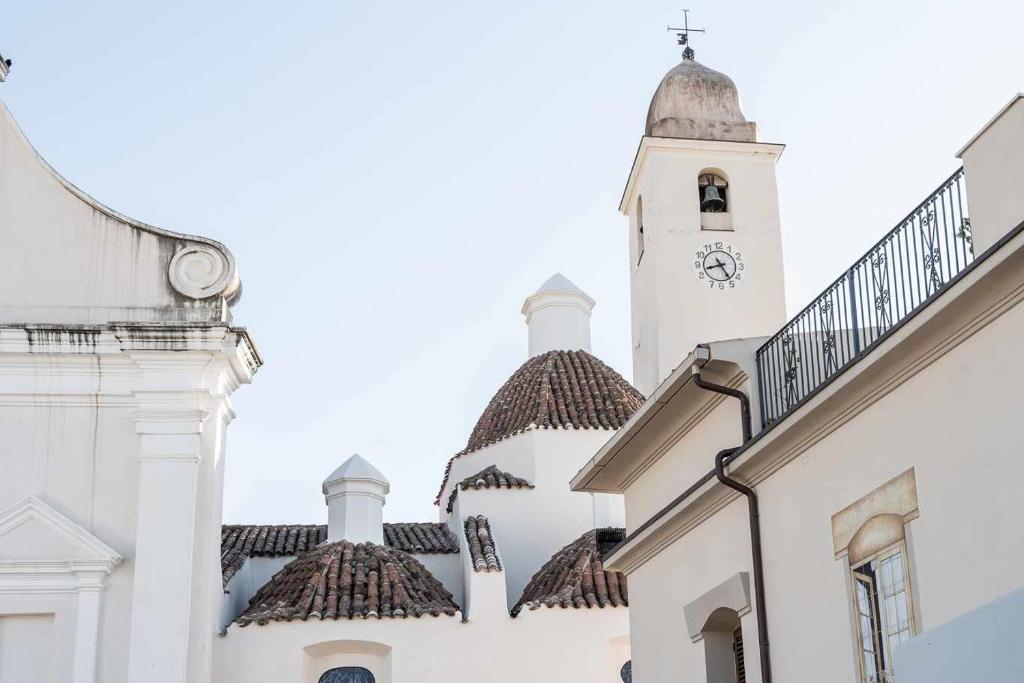 um edifício branco alto com uma torre de relógio em Domo Orise Alloggio in pieno centro em Orosei