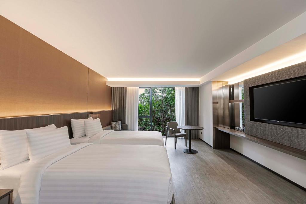 A twin room with two beds, a television and a window-side table and chair.