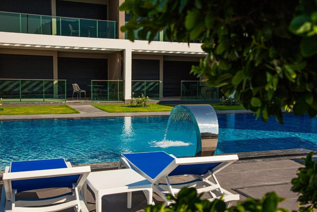 a swimming pool with two chairs and a fountain at Edem Apartments in Kemer