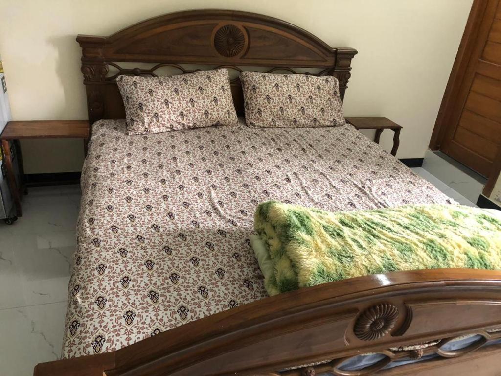 a bed with a wooden frame and pillows on it at Murree Oaks Tulip Block in Murree