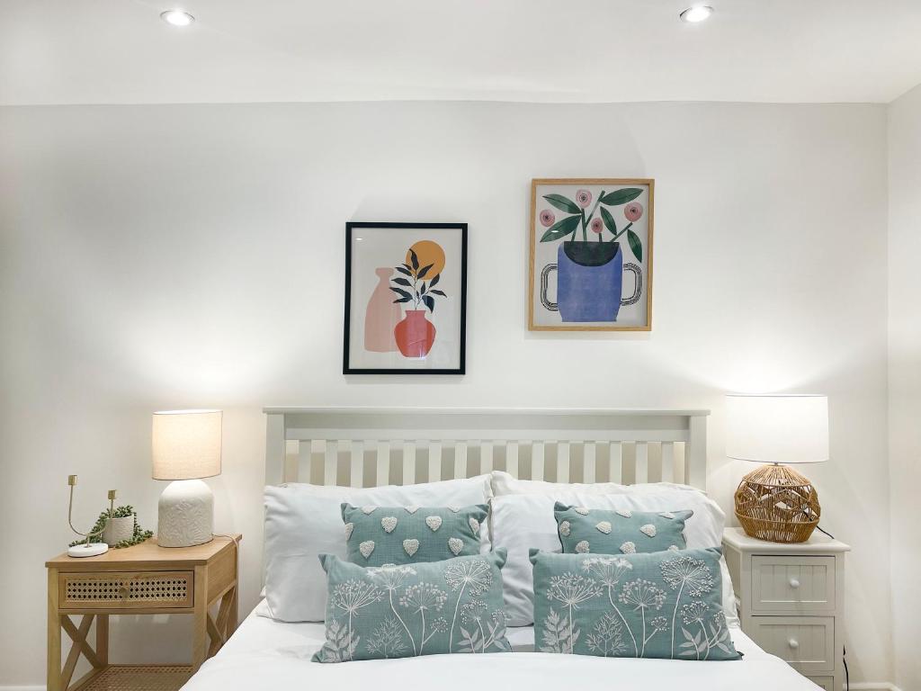 Schlafzimmer mit einem Bett mit Kissen und Gemälden an der Wand in der Unterkunft Sweet&Stylish 1 bed flat in CamdenTown in London