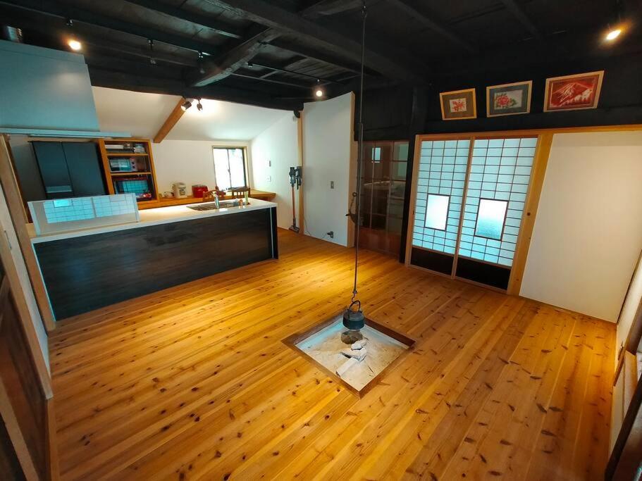 a living room with a kitchen and a wooden floor at ファミリー向けの一棟貸切り別荘「セキデンファーム」 in Warao