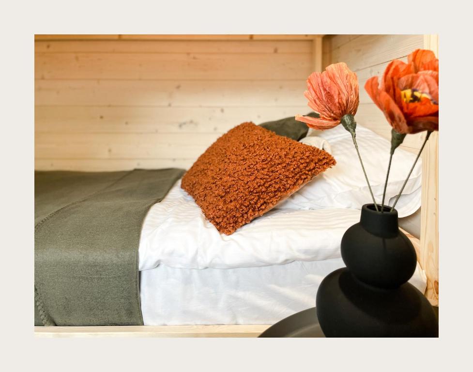 a vase with a flower on a table next to a bed at Port Sztynort in Węgorzewo