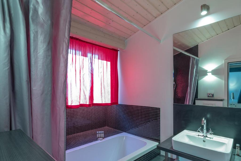 uma casa de banho com uma banheira, um lavatório e uma janela vermelha em Tralala Hotel Montreux em Montreux
