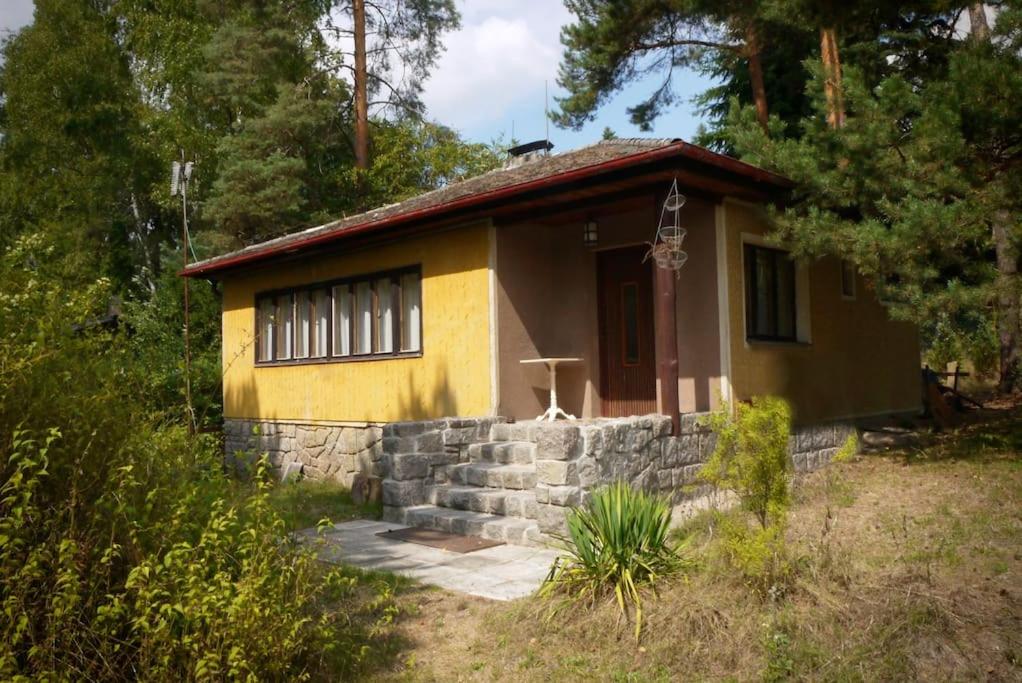 uma pequena casa amarela com uma parede de pedra em Chata na Vyžlovce em Vyžlovka