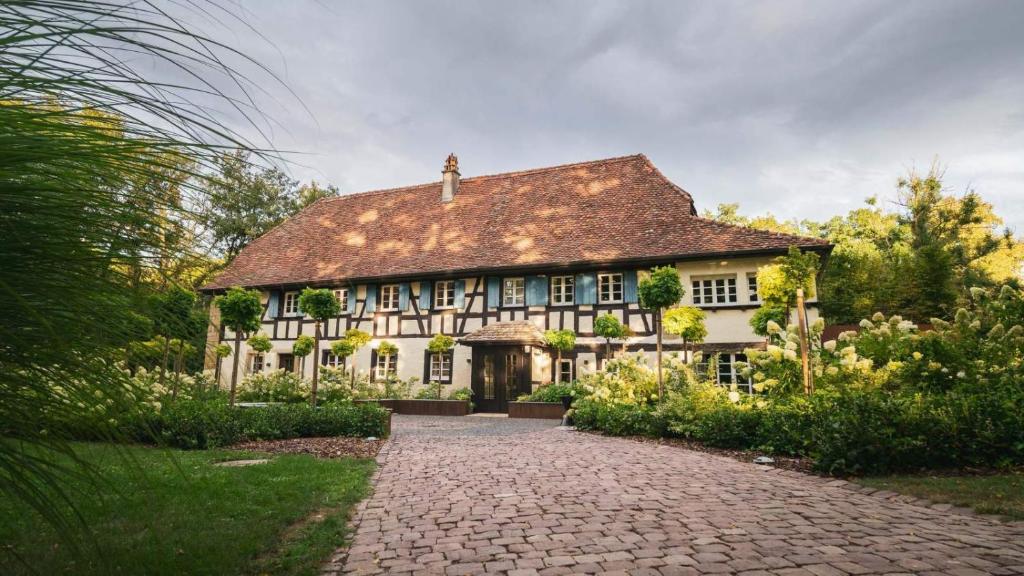 una grande casa bianca con un vialetto di mattoni di Domaine du Kaegy - Hébergements 5 étoiles a Steinbrunn-le-Bas