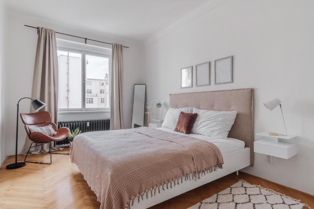 a white bedroom with a bed and a chair at Contemporary Flat in New Town by Prague Days in Prague