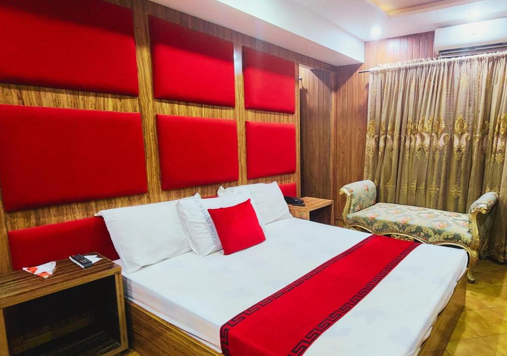 a bedroom with a bed with a red headboard and a chair at Sapphire Inn Motel Lahore in Lahore