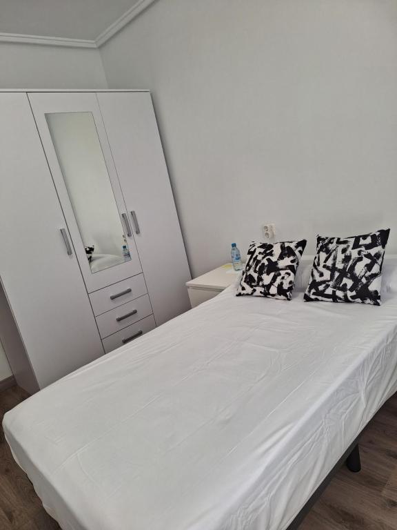 een slaapkamer met een bed, een dressoir en een spiegel bij Habitación individual in Valencia