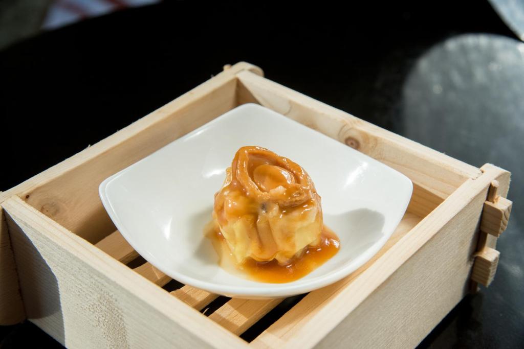 a small white plate with a donut in a wooden tray at The Reverie Saigon in Ho Chi Minh City