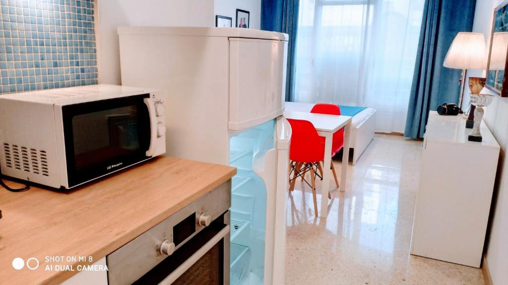 una cucina con forno a microonde e tavolo con sedia rossa di Hostal Estudios a Badalona