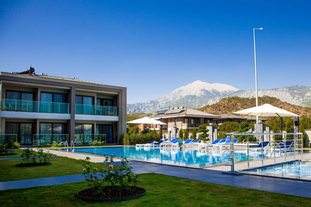 a hotel with a swimming pool with mountains in the background at Edem Apartments in Kemer