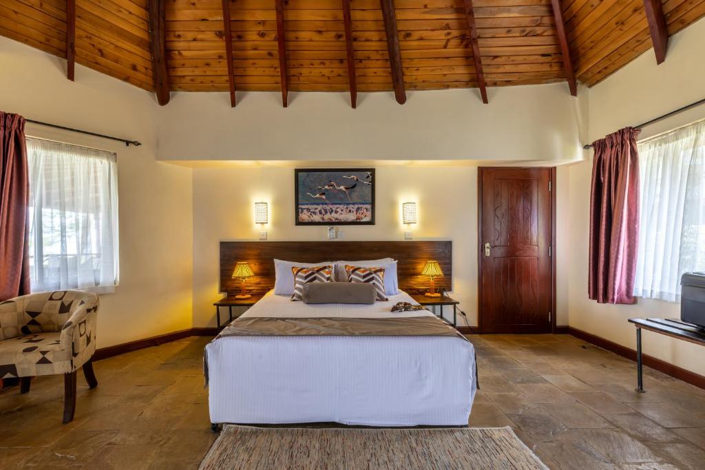 a bedroom with a large bed and a tv at Sentrim Elementaita Lodge in Elmenteita