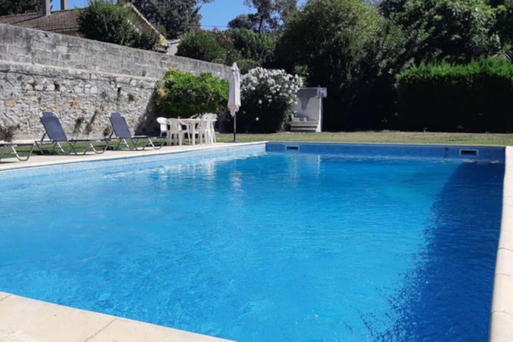 una gran piscina azul con 2 sillas y una mesa en Davaï appartement 6 personnes, en Pont-Saint-Esprit