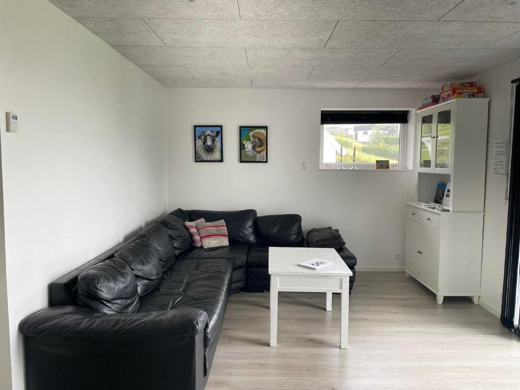 a living room with a black leather couch and a table at Perlan in Sørvágur